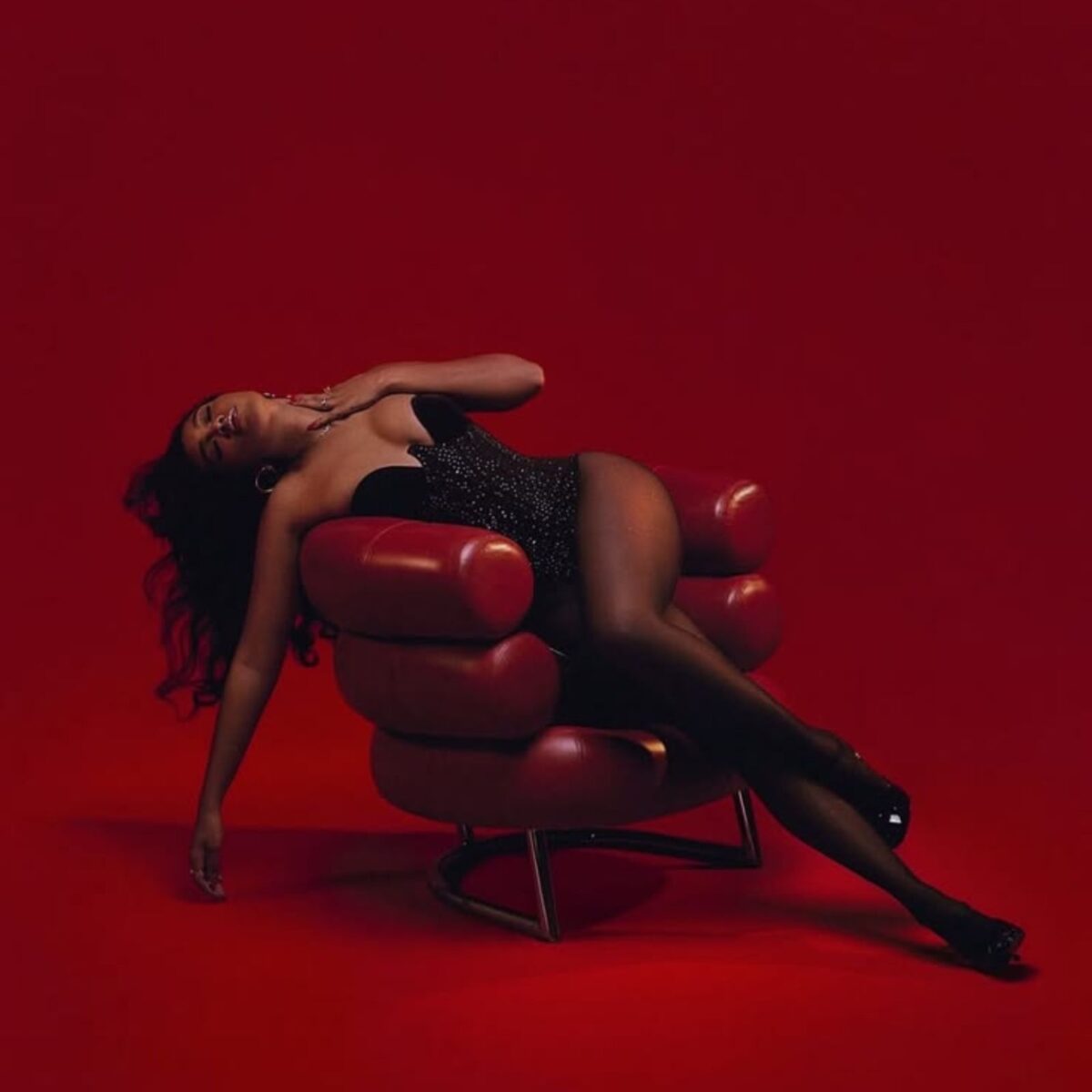 Femme allongée dans un fauteuil rouge, sur fond rouge.